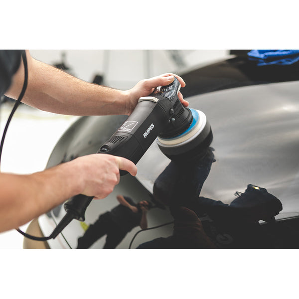 A person polishing the roof of a black car with a Rupes polisher.