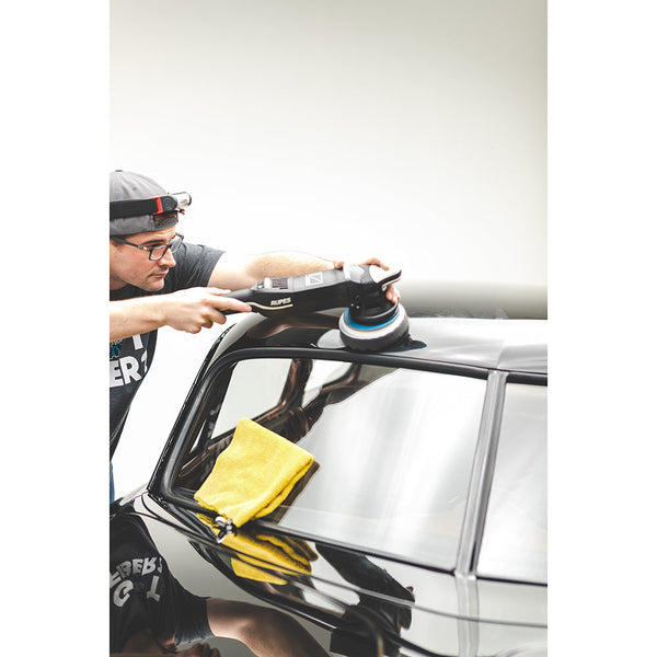 A person polishing the roof of a black car with a Rupes polisher.