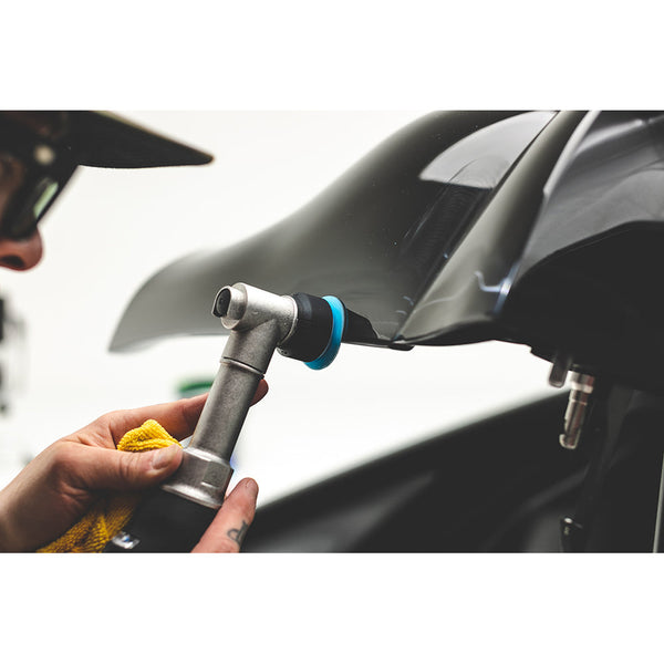 A closeup of someone polishing a black car with a small polisher.