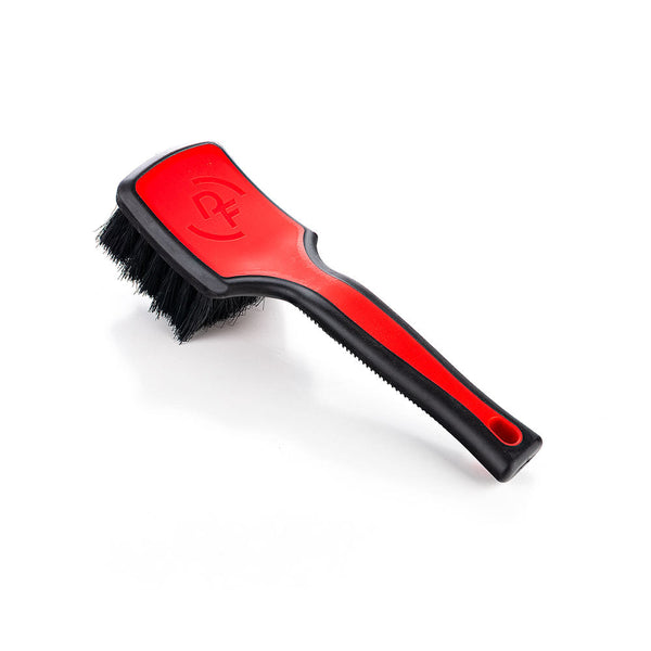 A red Detail Factory Interior Scrub Brush on a white background.