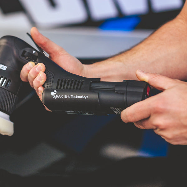 A closeup of a person holding the Rupes Mini Ibrid Polisher.