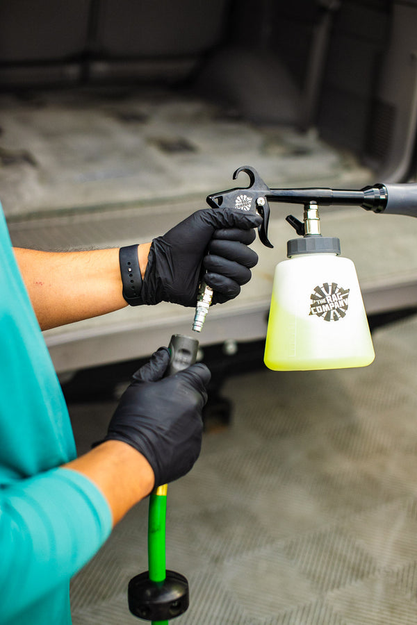 A person connecting an Ultra Air Blaster Plus to a hose with a background of the back of an SUV.