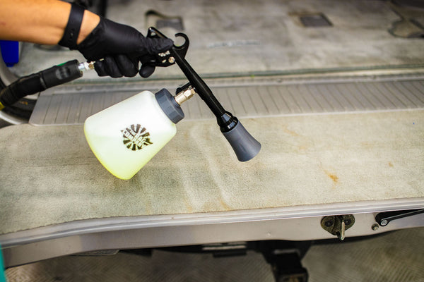 A person cleaning the carpet in the back of their car with The Rag Company Ultra Air Blaster Plus.