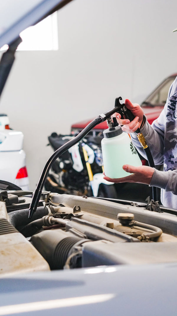 A person using The Rag Company Ultra Air Engine Blaster to clean the engine of a car.