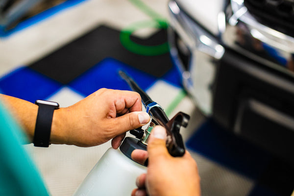 A person adjusting The Rag Company Ultra Air Engine Blaster with a blurry background of a car.