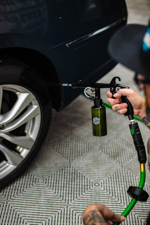 A person using The Rag Company Ultra Air Spray Applicator to clean off a tire.