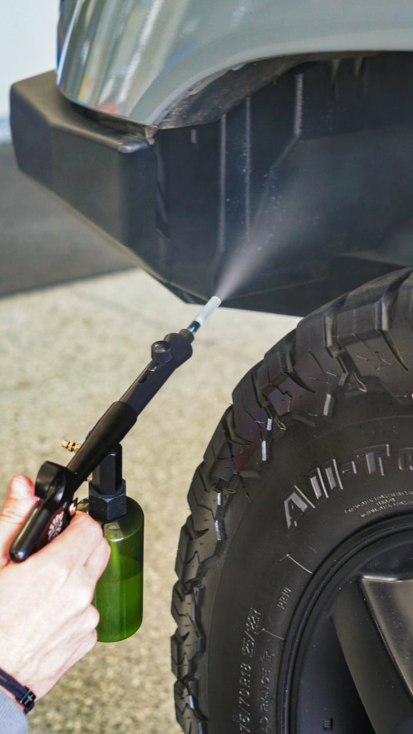 A person using The Rag Company Ultra Aire Spray Applicator to clean the wheel well.