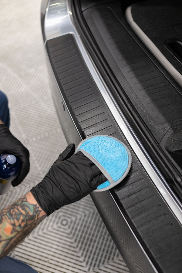 A person cleaning a car step with the TRC Ultra No Soak Round Detailing Applicator.