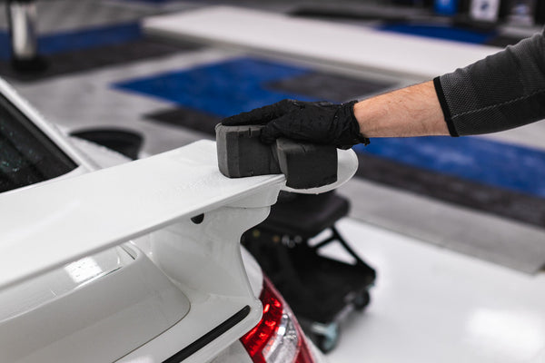 A person scrubbing a white car with a TRC Ultra Safe Sponge.