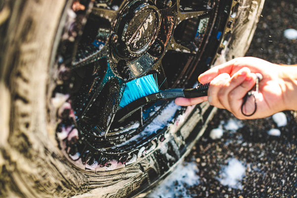 A person cleaning a tire rim with The Rag Company Ultra Wheel and Body Brush.