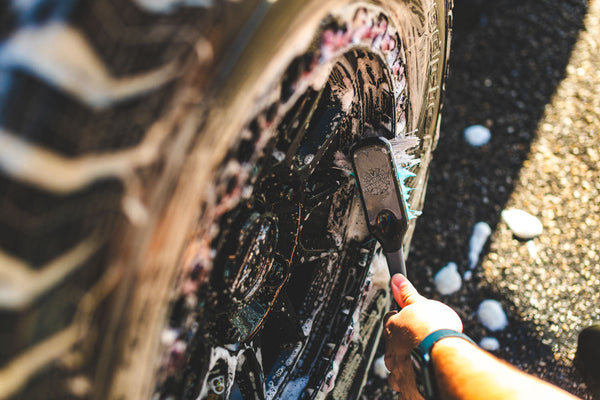 A person cleaning a tire rim with The Rag Company Ultra Wheel and Body Brush.